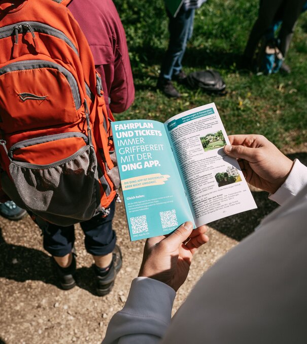Person hält den DING Flyer über Fahrpreise