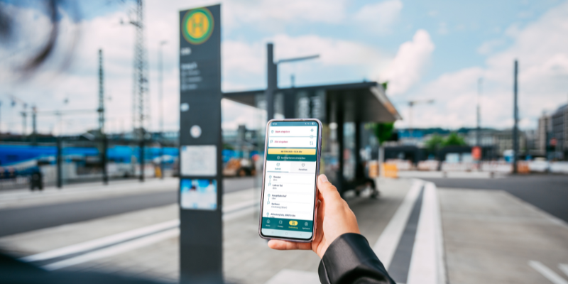 Person hält Handy mit digitaler Fahrauskunft in der Hand